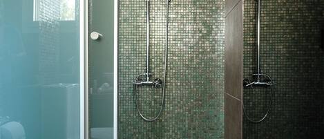 A shower area with a glass door and a tiled wall.
