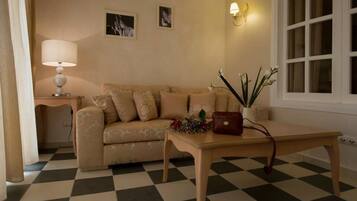 A living room with a checkered floor, a sofa, a table with a vase and flowers, a lamp, and a wall-mounted light fixture.