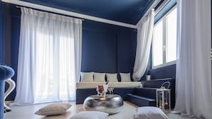 A modern living room with a blue accent wall, a sofa, a coffee table, and a window with white curtains.