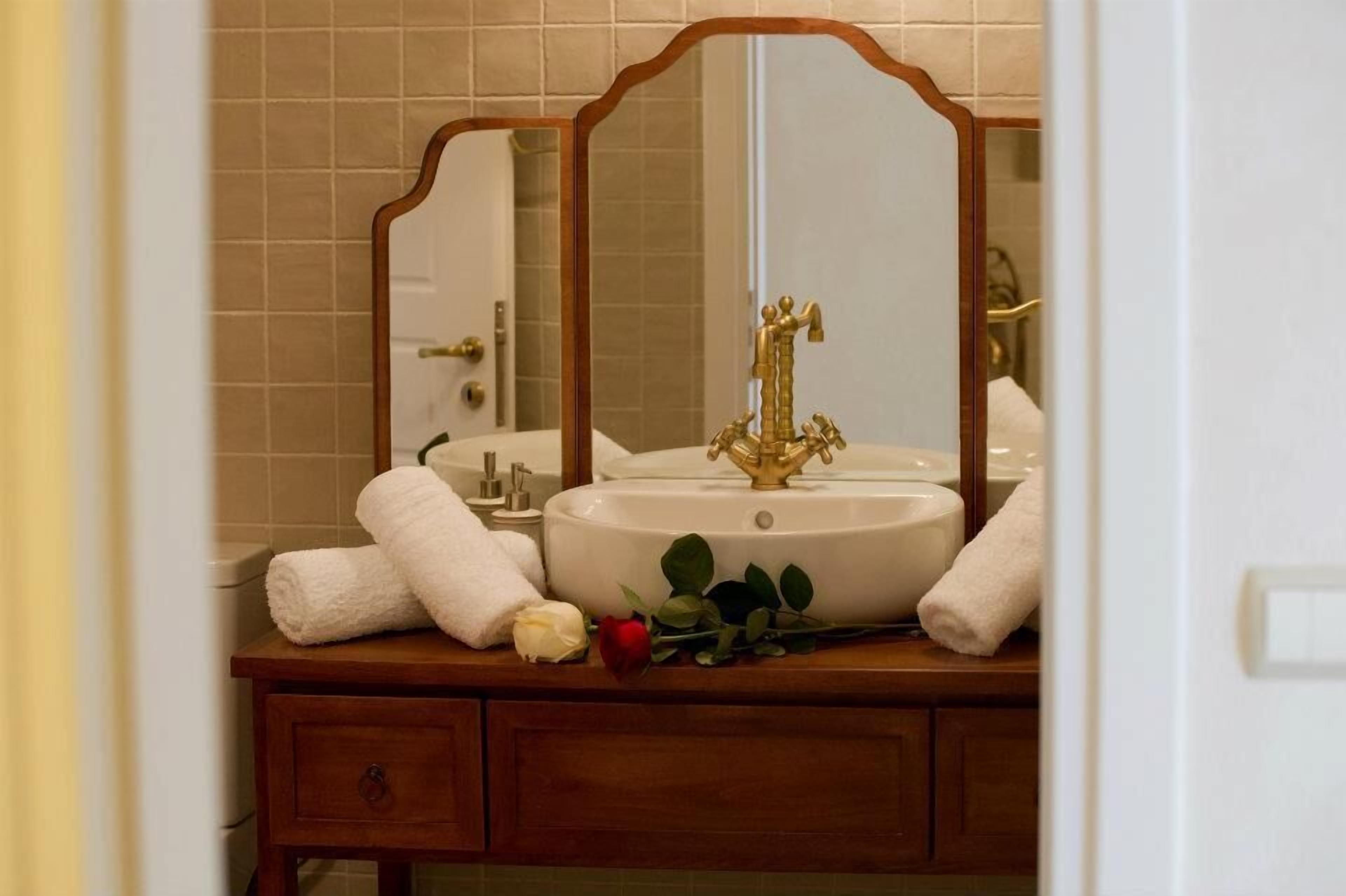 A bathroom with a white sink, two mirrors, and a wooden vanity.