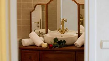 Une salle de bain avec un lavabo blanc, deux miroirs et un meuble-lavabo en bois.