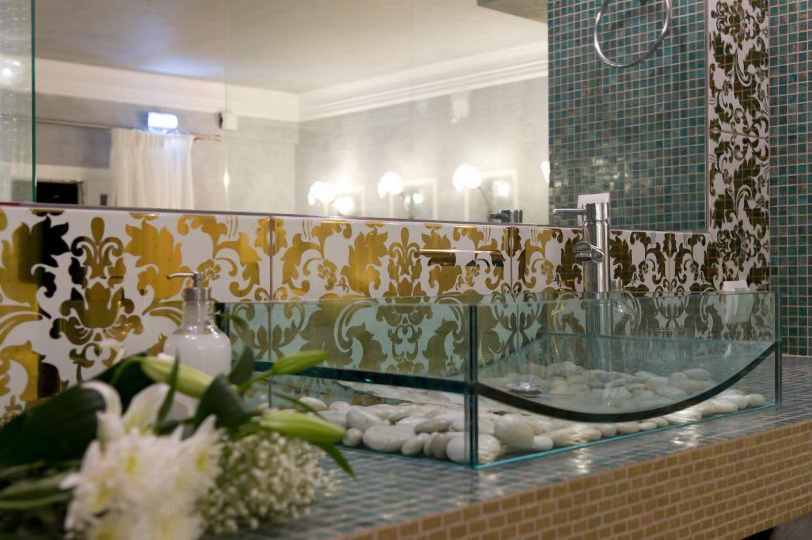 A bathroom with a glass-enclosed sink, decorative tiles, and a mirror.