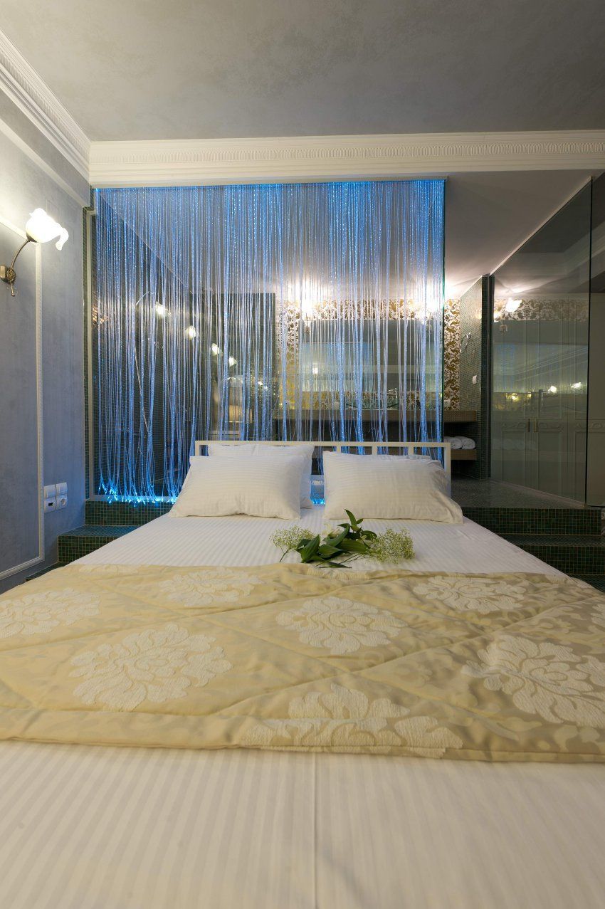 A hotel room with a large bed, a bedside table, a nightstand, and a view of a balcony.