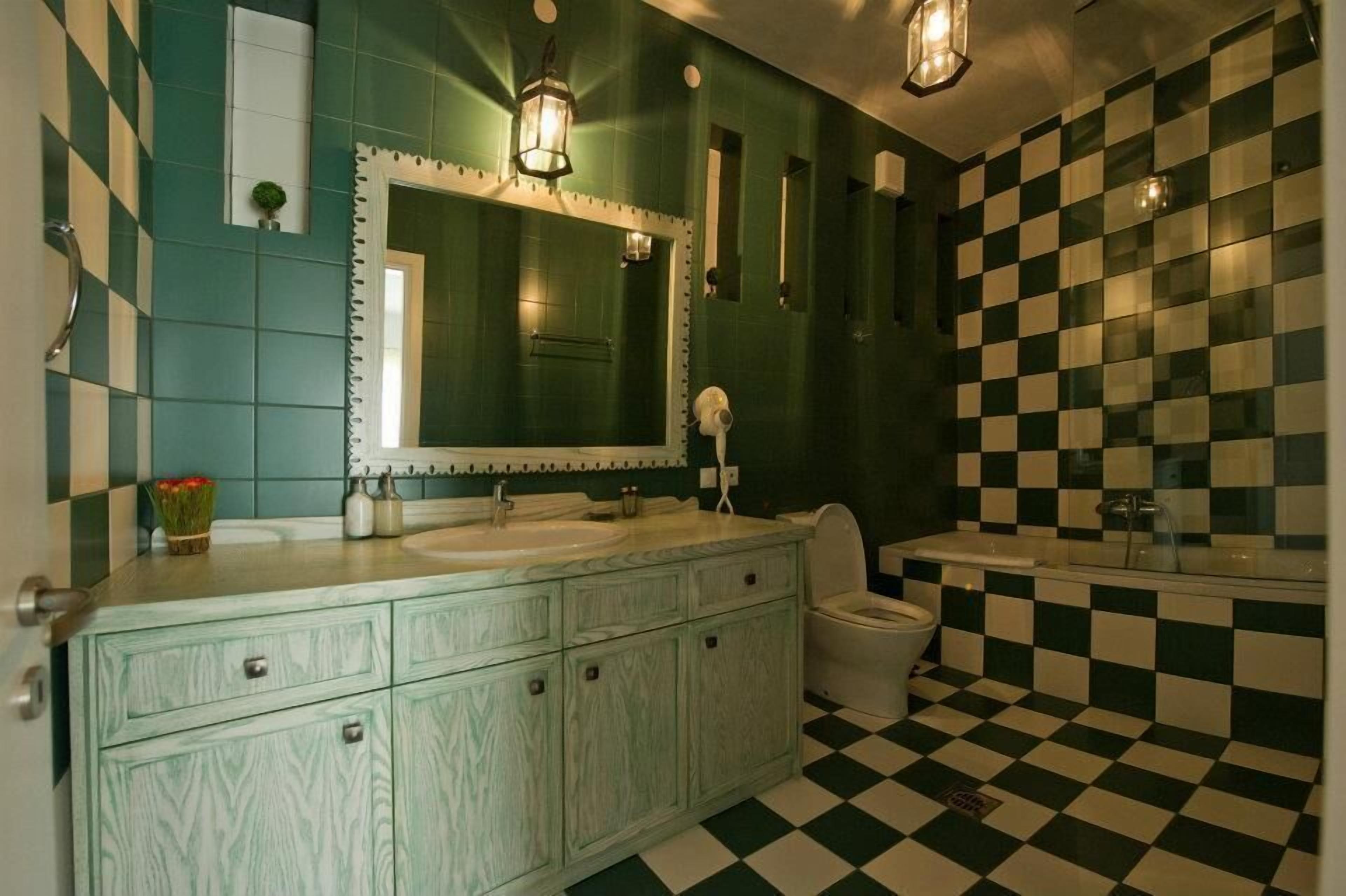 A bathroom with a checkered floor, a sink, a toilet, and a mirror.