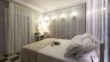 Un dormitorio con cama, mesita de noche, espejo y ventana con cortinas.