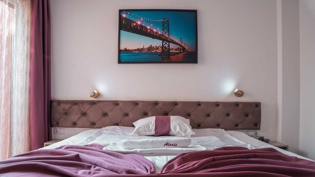 Hotelkamer met een bed, een hoofdeinde, een nachtkastje en een aan de muur hangend schilderij van een brug.