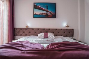 A hotel room with a bed, a headboard, a nightstand, and a wall-mounted picture of a bridge. - Hotel Alexis (Cluj-Napoca)