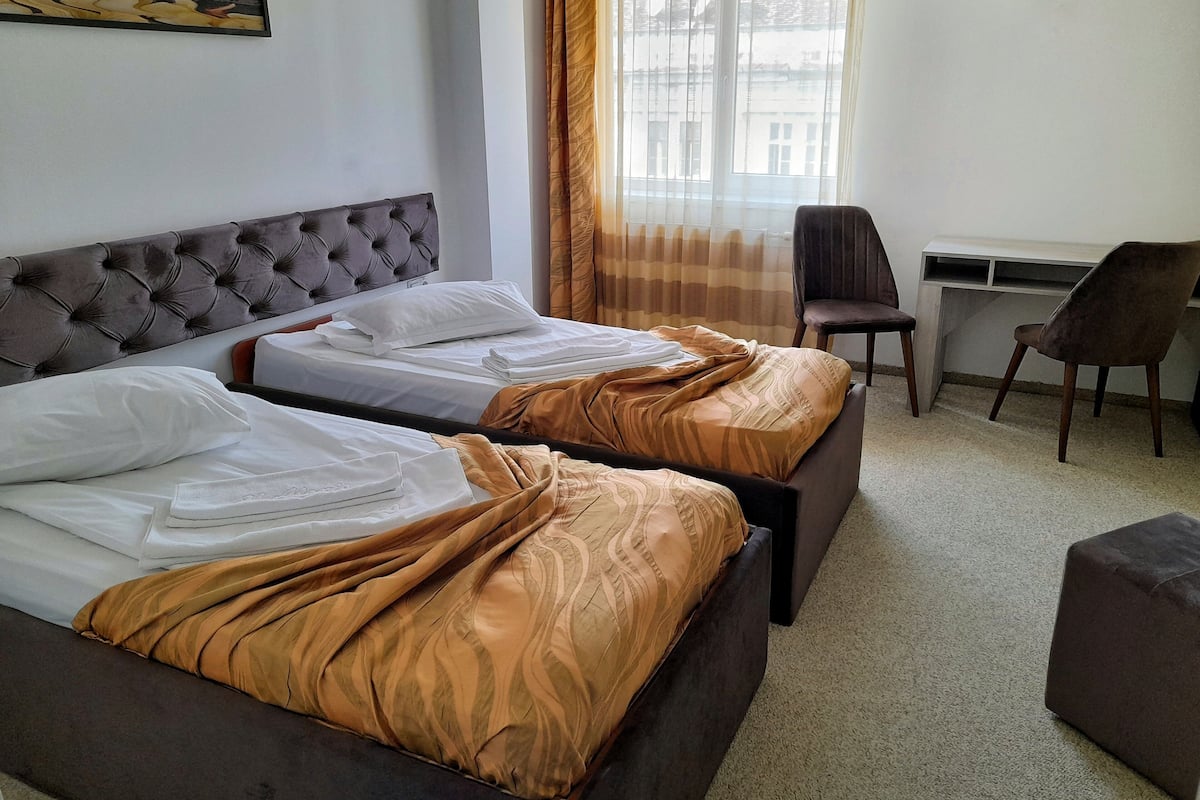 A hotel room with two beds, a desk, and a chair.