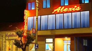 Hotel Alexis met een neonbord, een parkeersignaal en een zichtbare ingang.