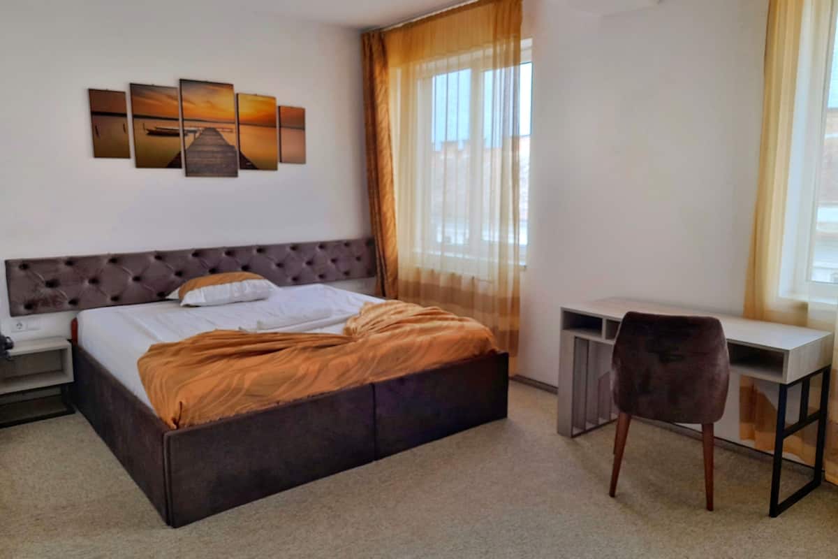A bedroom with a bed, a desk, and a chair.