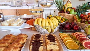 Un bufé con diferentes opciones de comida, entre ellas frutas, pastelería y pan.