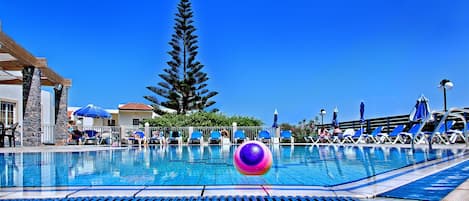 Una piscina al aire libre de temporada, sombrillas