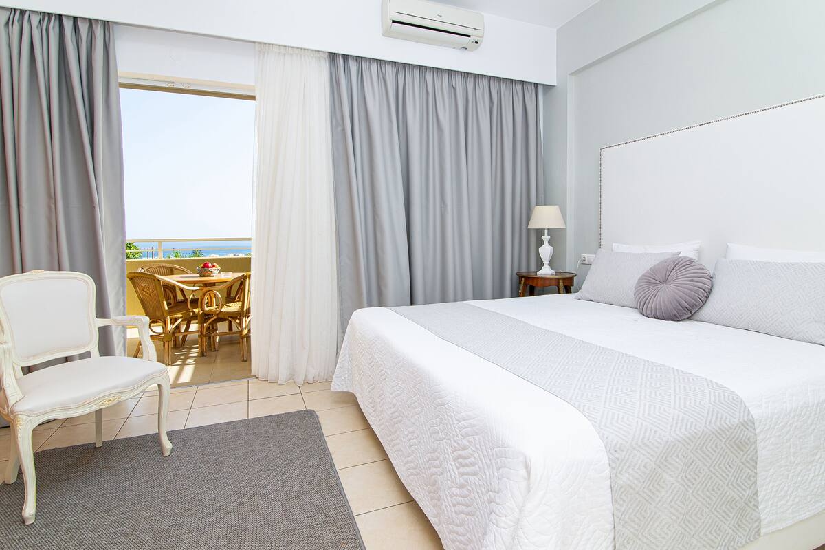 Una habitación de hotel con cama, una silla, una mesa y vista al mar.