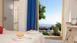 Habitación de hotel con cama, toallas, ducha y vista al mar.