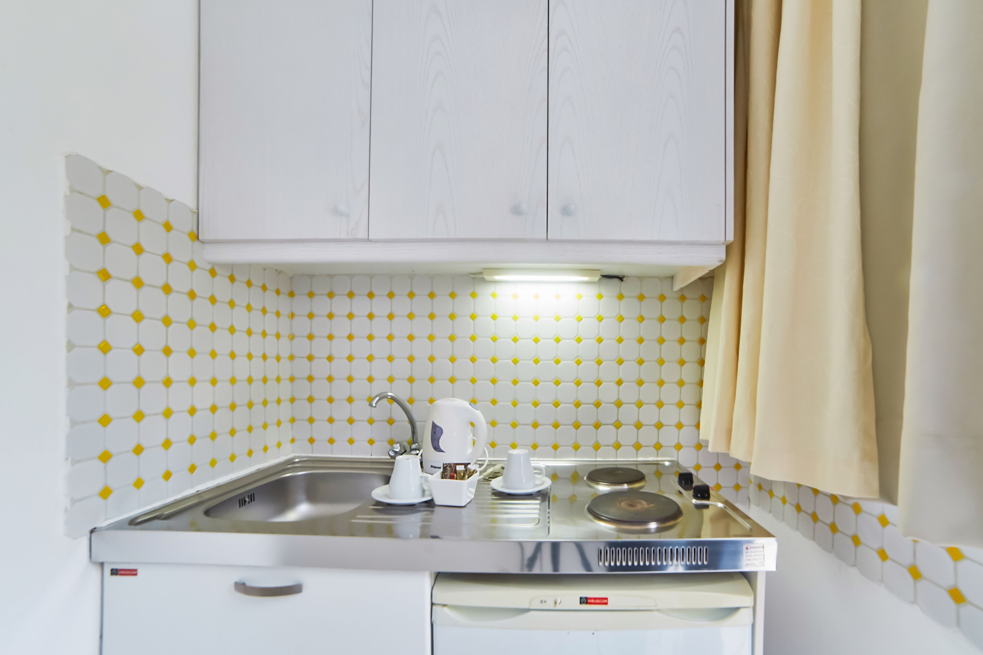 A compact kitchen with a sink, stove, and cabinets.