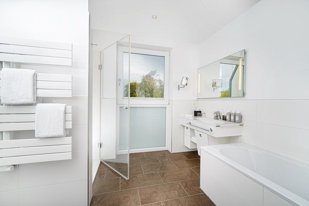 Un baño moderno con mampara de vidrio, accesorios blancos y un espejo grande.