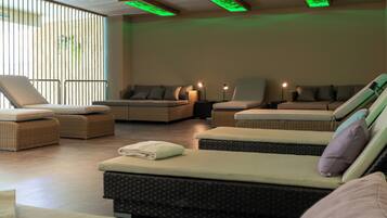Un cuarto de spa con varias sillas reclinables, un ventanal con persianas verticales e iluminación ambiental verde.