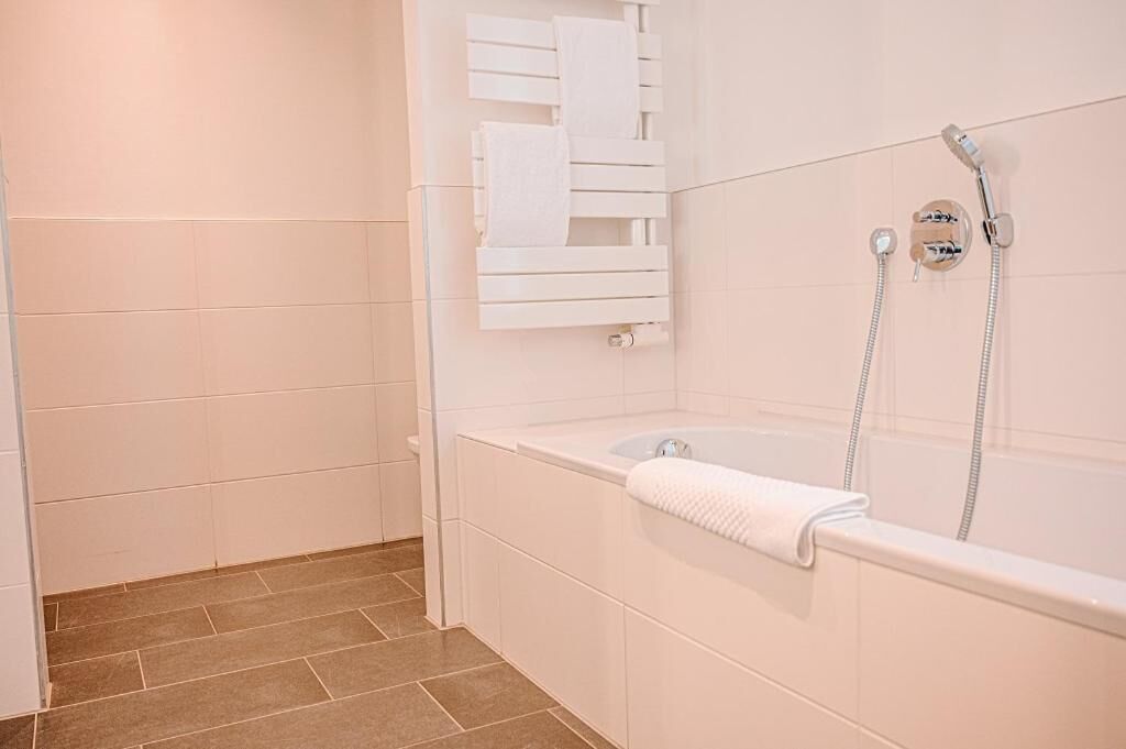 A bathroom with a bathtub, a towel rack, and a shower.