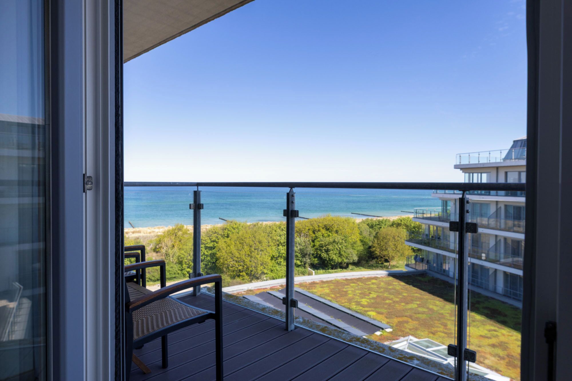 Un balcon avec vue sur l’océan et un bâtiment moderne.