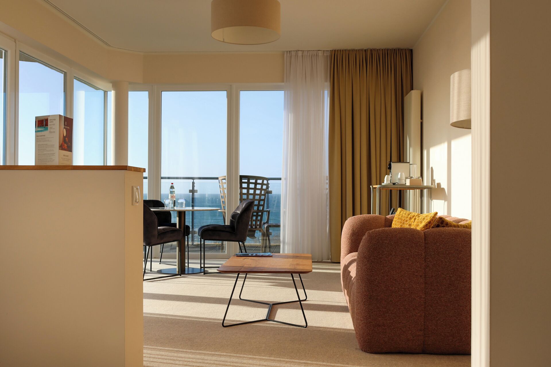 Une chambre d’hôtel avec un balcon, un canapé, une table et une chaise.