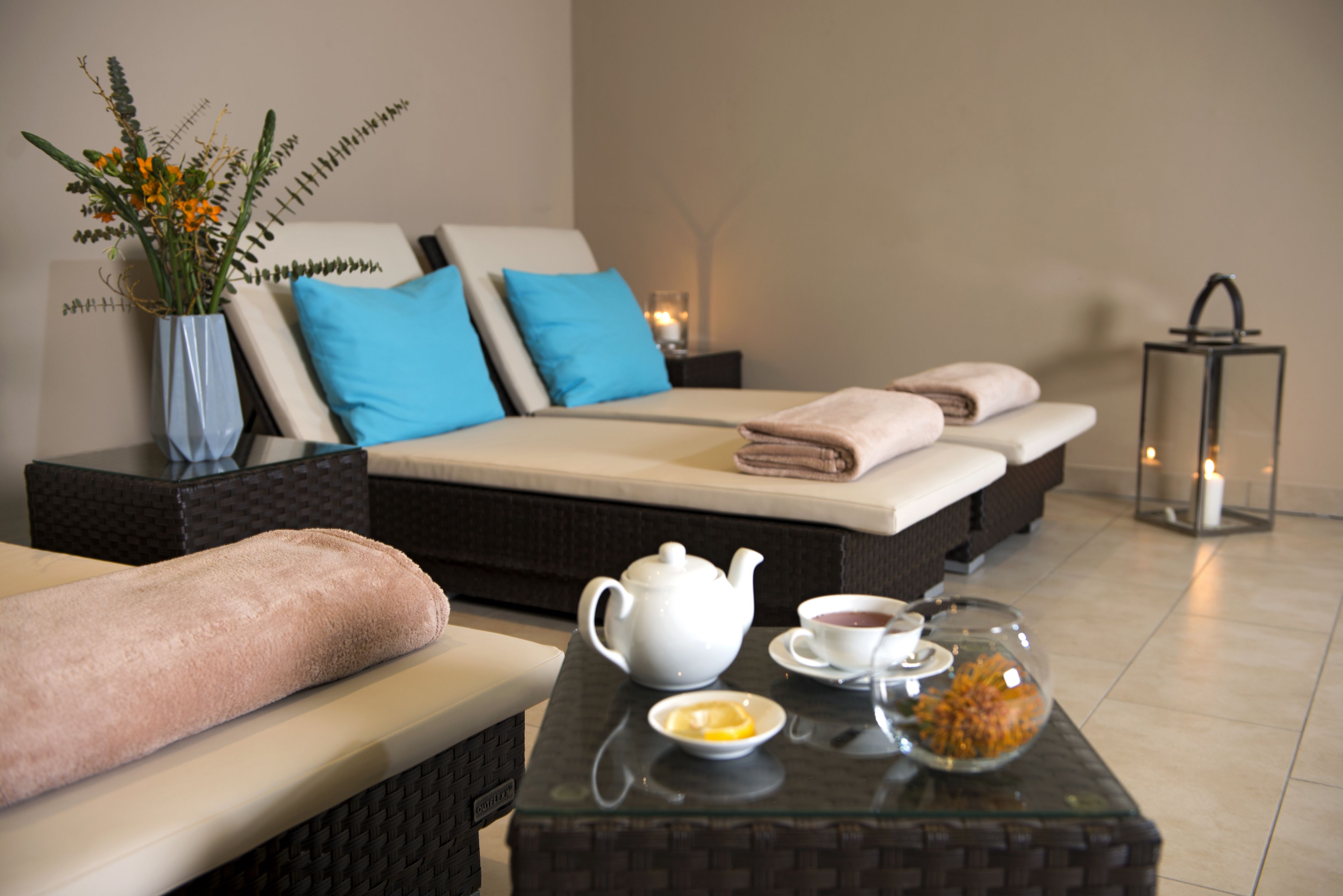 Ein modernes Zimmer mit einer Couch, einem Glastisch mit Teekanne, Tassen und einer Obstschale.