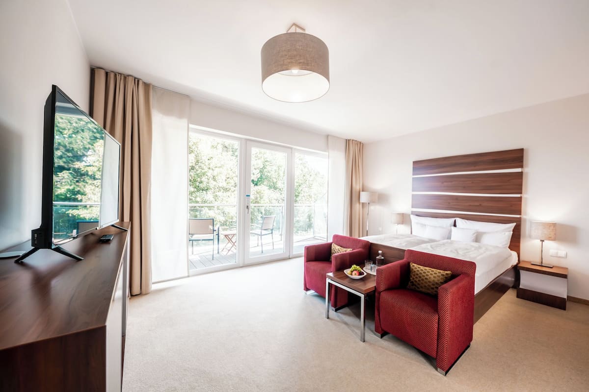 A hotel room with a bed, a desk, a chair, a table with fruit, and a TV.