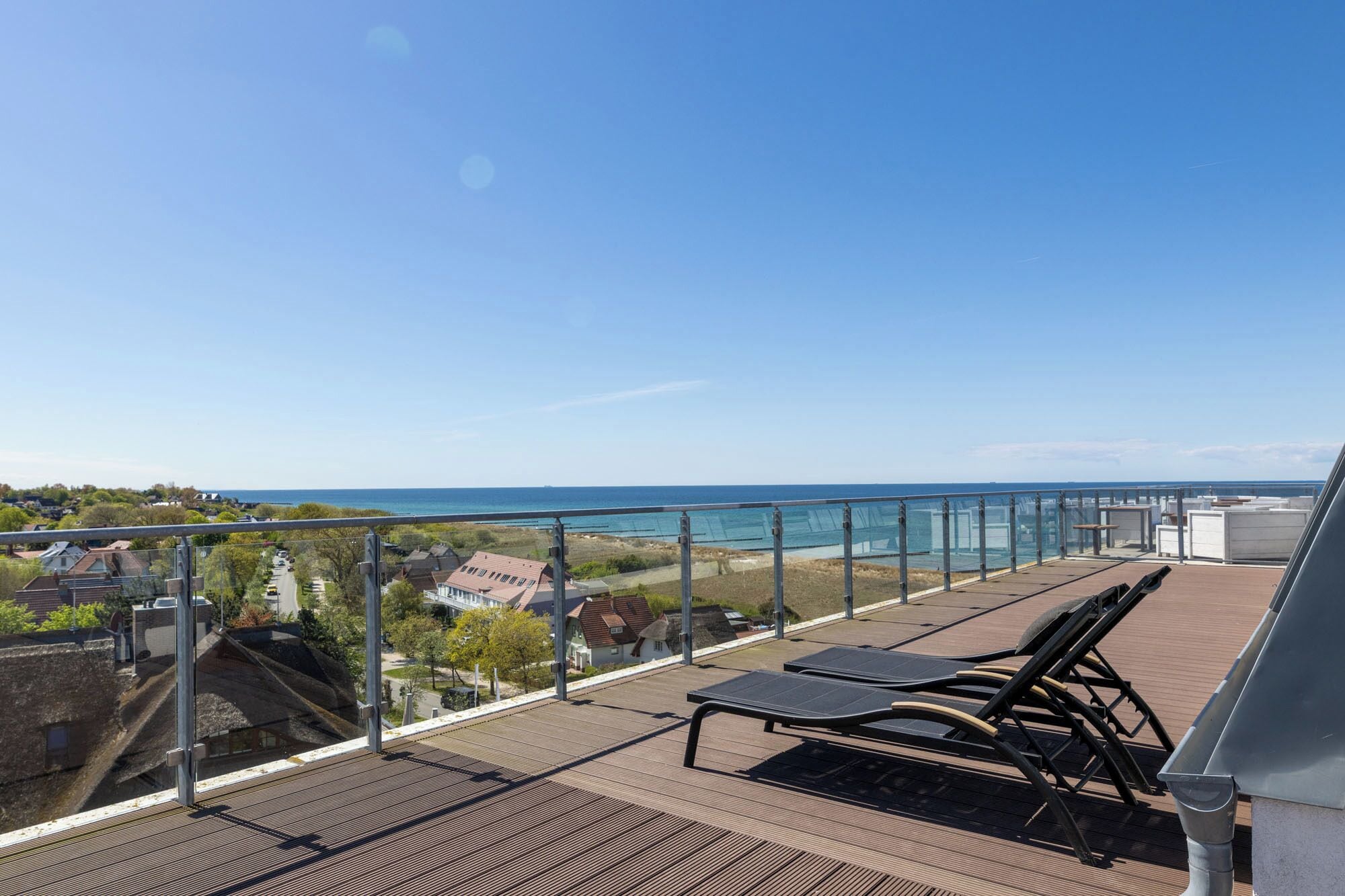 Un balcon avec vue sur la mer, un fauteuil de relaxation et une rambarde en verre.