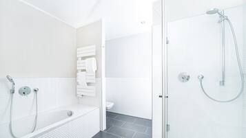A modern bathroom with a bathtub, a shower, and a toilet.