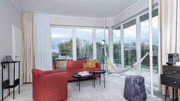 Un hotel moderno con un sofá rojo, una mesita, una hamaca y vistas al exterior a través de amplios ventanales.