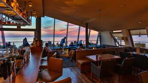 A bar area with seating and a view of the sunset over the water. - THE GRAND Ahrenshoop (Ostseebad Ahrenshoop)