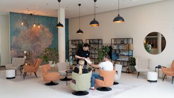 Eine moderne Lobby mit Sitzbereichen, einem großen abstrakten Wandbild und einer Rezeption.