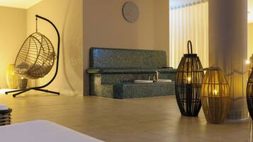 A modern spa room with a hanging chair, a massage table, a small sink, and decorative lanterns.