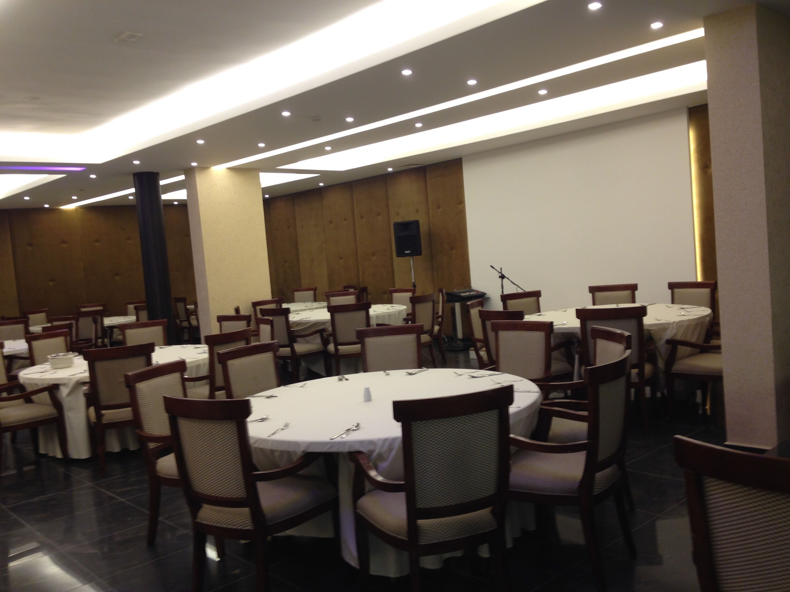 A conference room with round tables and chairs, equipped with a speaker and a projector.