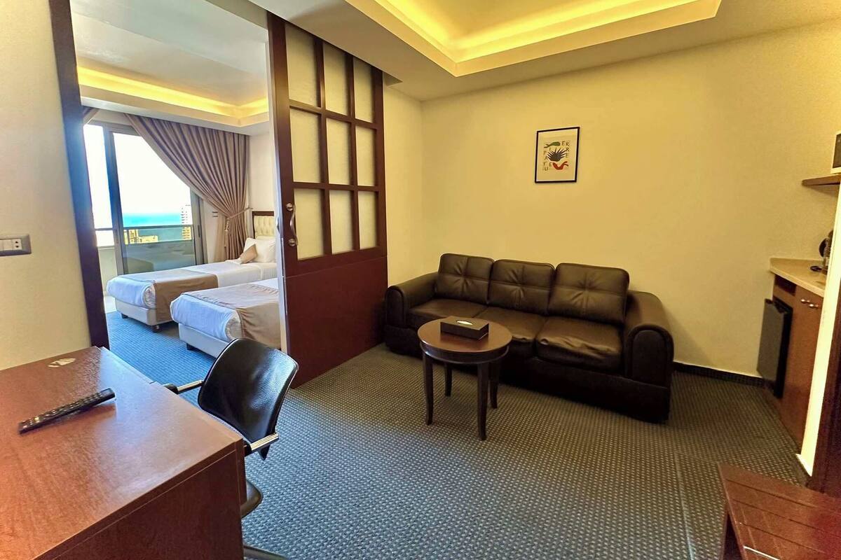 A hotel room with a bed, a sofa, a desk, and a small table.