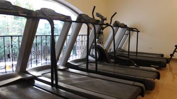 A row of treadmills in a room with a large window and a balcony.