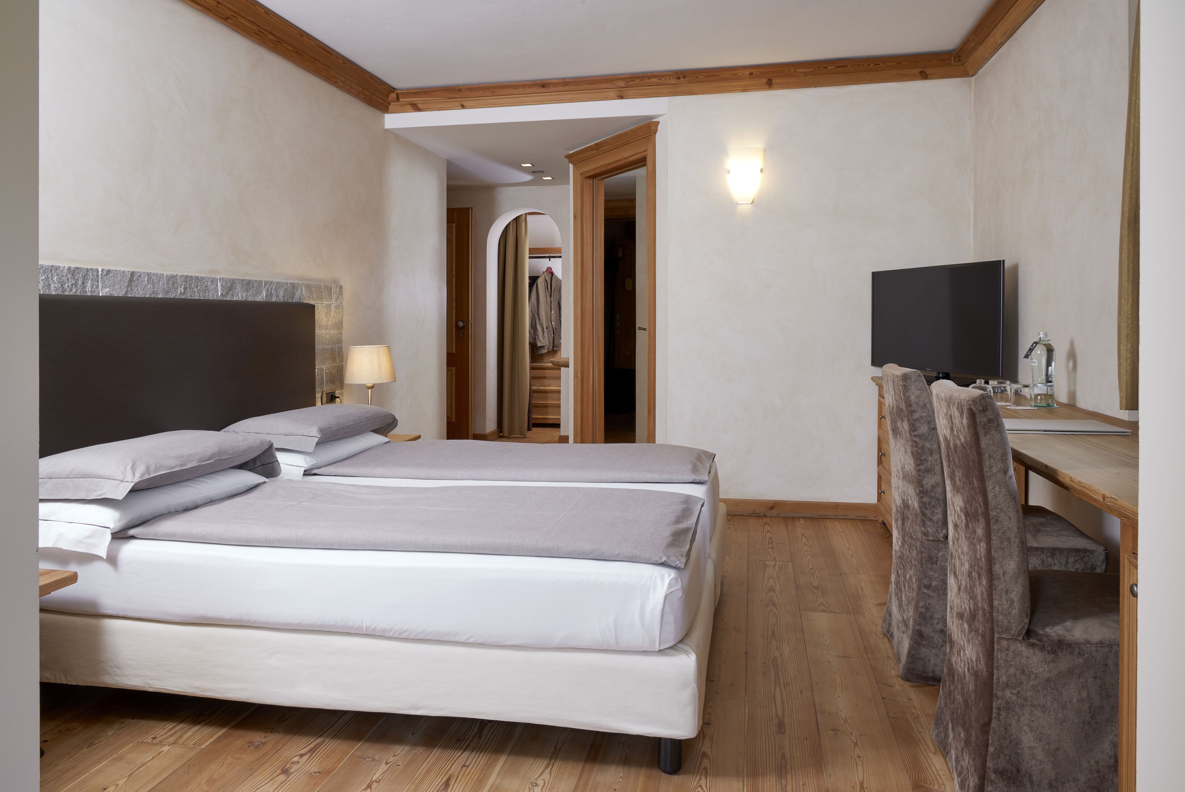Une chambre d’hôtel comprenant un lit, un bureau avec une chaise, une télévision et un miroir.