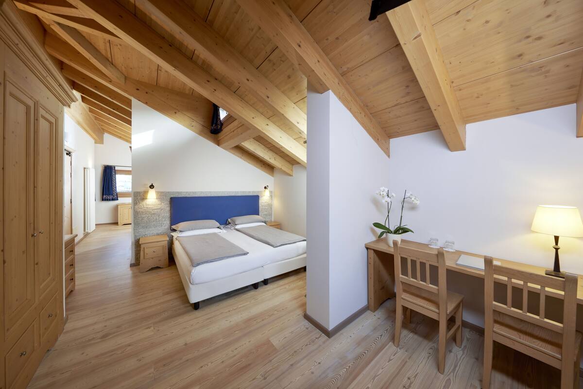 Un dormitorio con techo de madera, una cama, un escritorio y una silla.