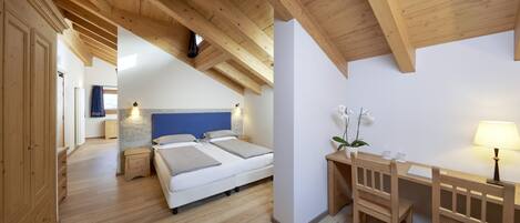 Un dormitorio con techo de madera, una cama, un escritorio y una silla.