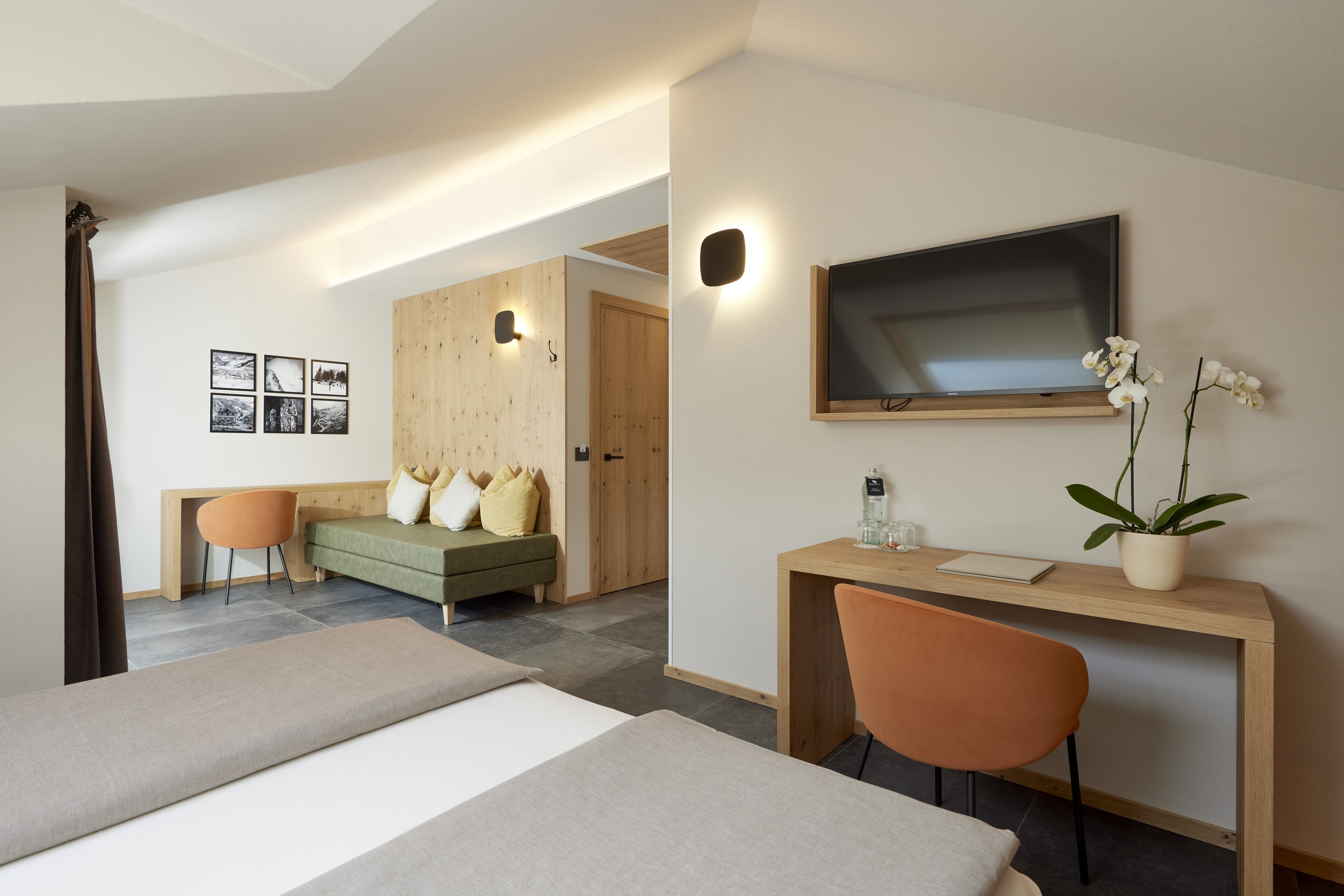 A modern hotel room with two beds, a desk, a chair, a TV, and a potted plant.