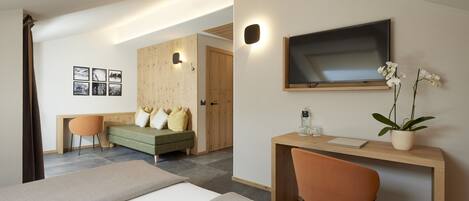 A modern hotel room with two beds, a desk, a chair, a TV, and a potted plant.