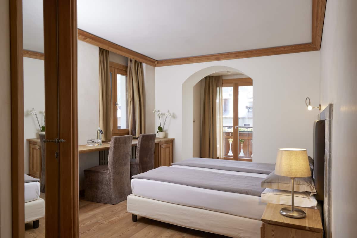 Una habitación de hotel con cama, escritorio, silla y lámpara.