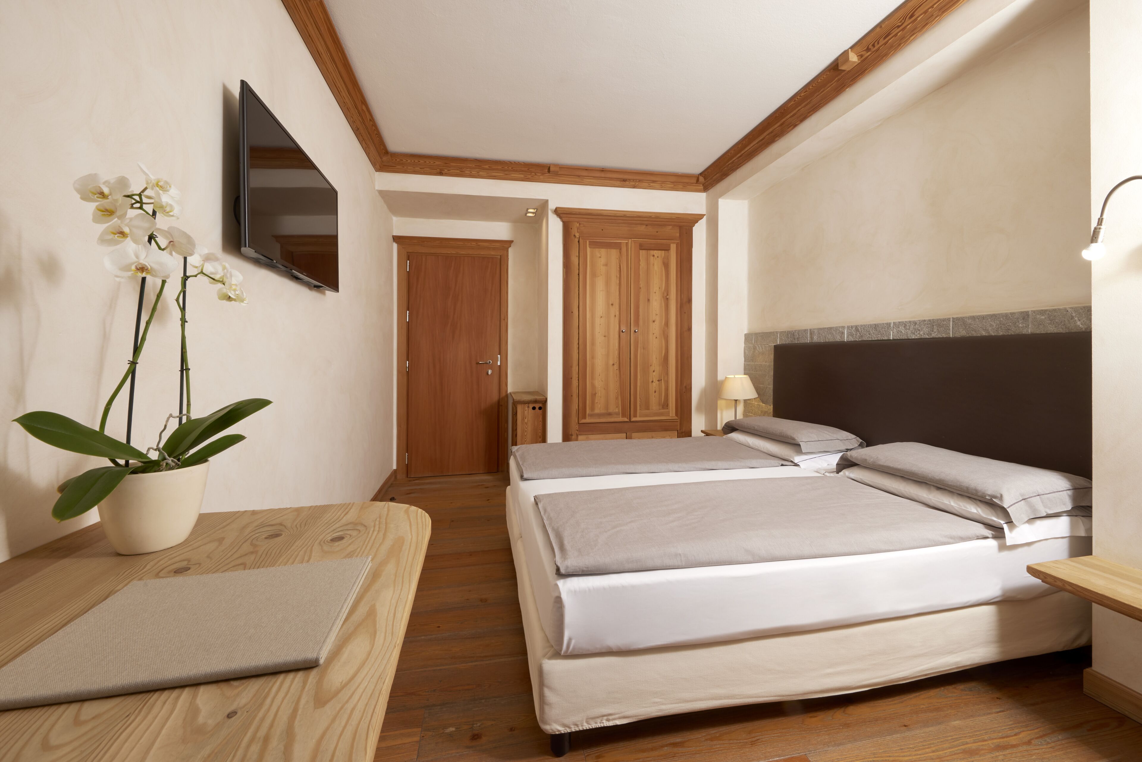 Une chambre d’hôtel avec un lit, une table de chevet, une lampe et une plante en pot.