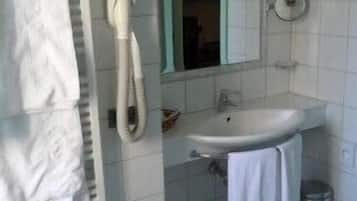 A bathroom with a white sink, a mirror, a towel rack, and a shower.