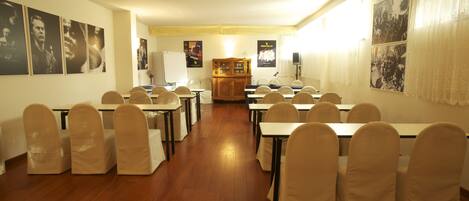 A conference room with tables and chairs, posters on the walls, and a wooden cabinet.