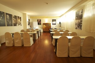 Un salón de conferencias con mesas y sillas, carteles en las paredes y un armario de madera.