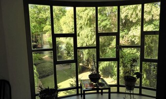 Habitación con un amplio ventanal que da a un jardín. Hay una mesa con una planta y un libro encima.