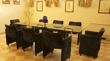 Une salle de conférence avec une table en verre, des chaises noires et des œuvres d’art encadrées accrochées aux murs.