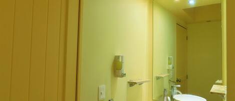 A bathroom with a large mirror, a sink, and a towel rack.