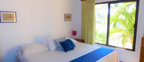 A bedroom with a bed, a window with curtains, a ceiling fan, and a red lamp.