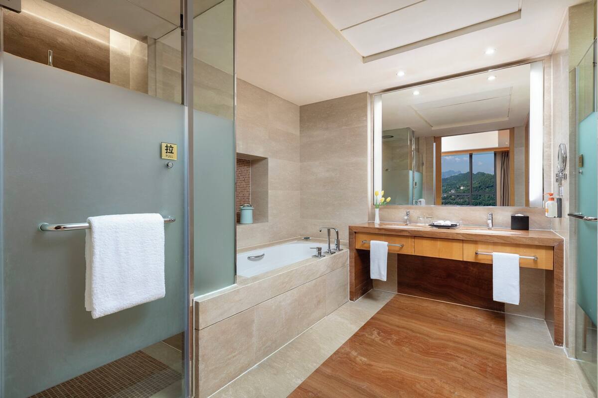 Un baño moderno con cabina de ducha de vidrio, un espejo grande y un tocador doble.